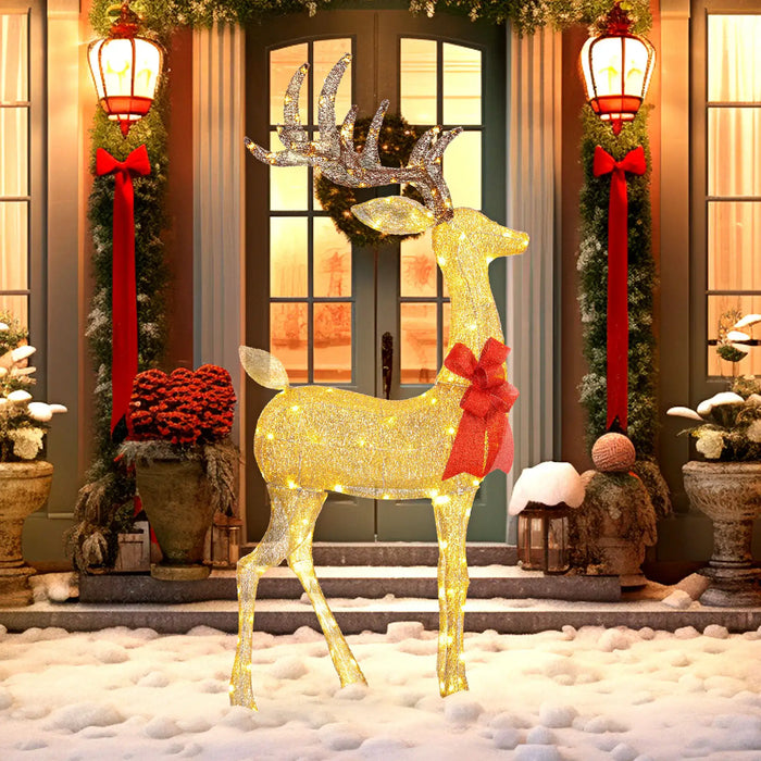 Glowing golden reindeer Christmas decoration with red bow in snowy front yard at holiday-lit house entrance