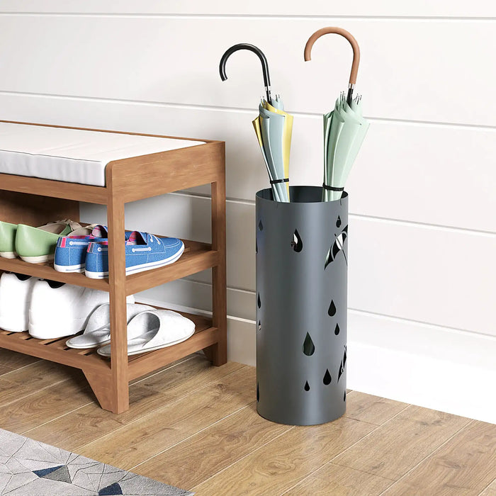 Umbrella stand with umbrellas next to a wooden shoe rack with shoes on a wooden floor.