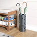 Umbrella stand with umbrellas next to a wooden shoe rack with shoes on a wooden floor.