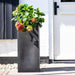 Tall black double-walled flower pot with hydrangeas outside a white house entrance