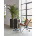 Urban smooth black flower pots with green plants next to a leather chair in modern living room
