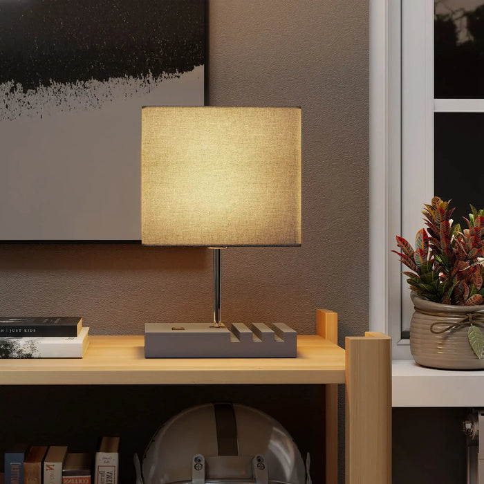 Table lamp on a desk with a plant and books in a room setting