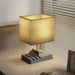 Table lamp with a square beige shade on a wooden surface.