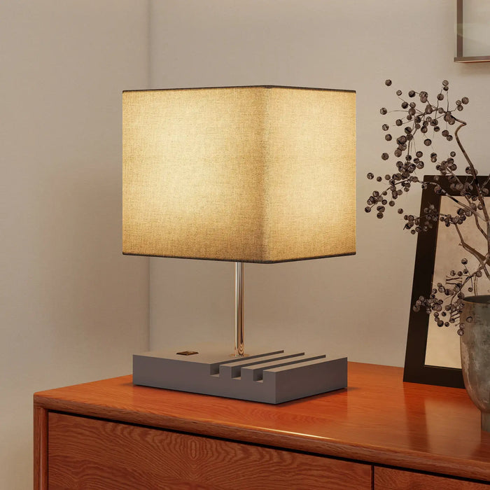 Table lamp with a beige shade on a wooden surface, with a neutral background