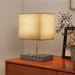 Table lamp with a beige shade on a wooden surface, with a neutral background
