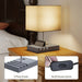 Table lamp with phone stand and on/off rocker switch on a bedside table.