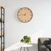 Rustic wooden wall clock with silent quartz movement on white brick wall above minimal white table and gray sofa