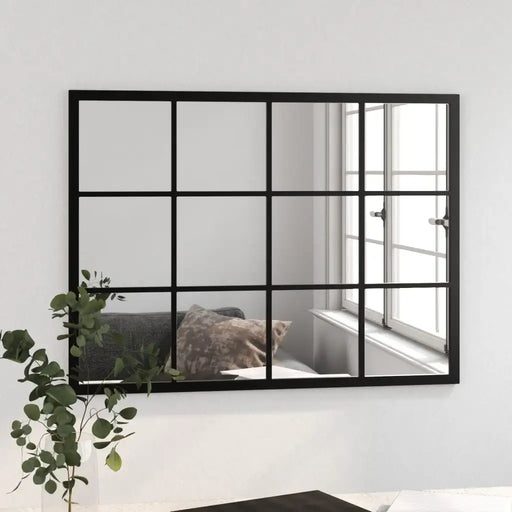 Black-framed mirror with grid design on a white wall, reflecting a room with a window.