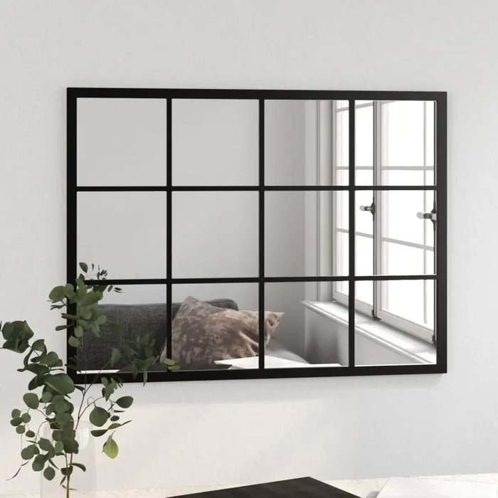 Black-framed mirror with grid design on a white wall, reflecting a room with a window.