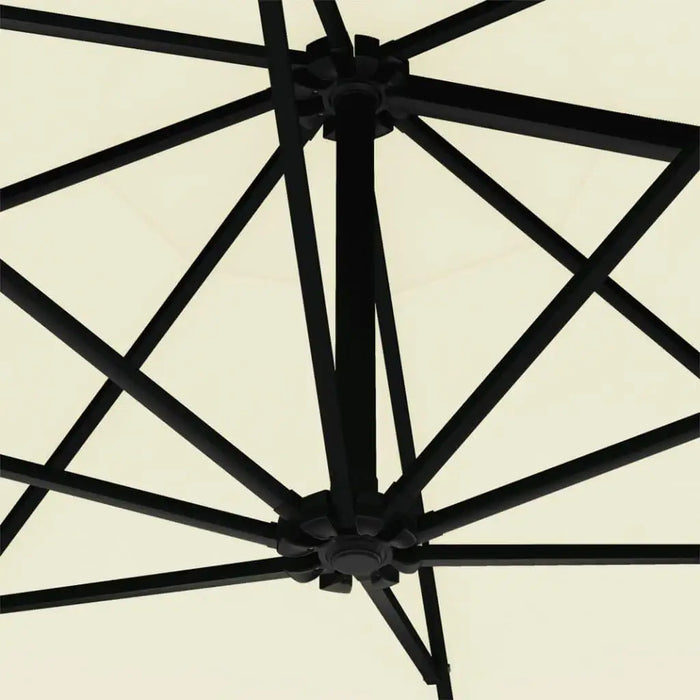 Close-up of black metal ribs and crank hub on sand-colored wall-mounted parasol canopy.