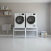 Two white front-loading washing machines on a white stand in a modern laundry room.
