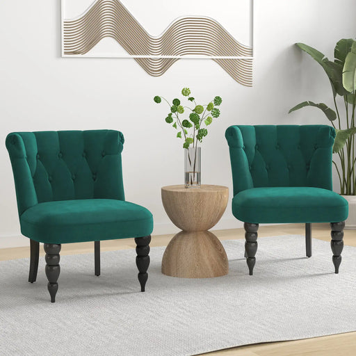 Two green chairs in a room with a wooden side table and decorative wall art.