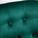 Close-up of a green upholstered headboard with button tufting.