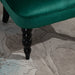 Close-up of a green upholstered chair leg on a textured carpet