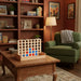 Wooden 4-in-a-row board game on a coffee table in cozy living room with bookshelf.