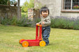 Baby with eco-friendly wooden walker on grass, outdoor garden, Moover brand