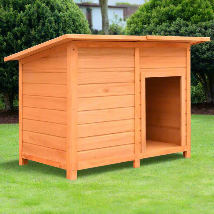 Outdoor wooden dog house with slanted roof on grass, surrounded by green bushes