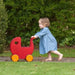 Toddler pushes cherry red wooden dolls pram toy outdoors, birch veneer, yellow wheels