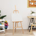Natural pinewood easel with blank canvas in modern art studio setting
