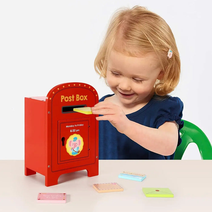 Child playing with a toy post box on a light background