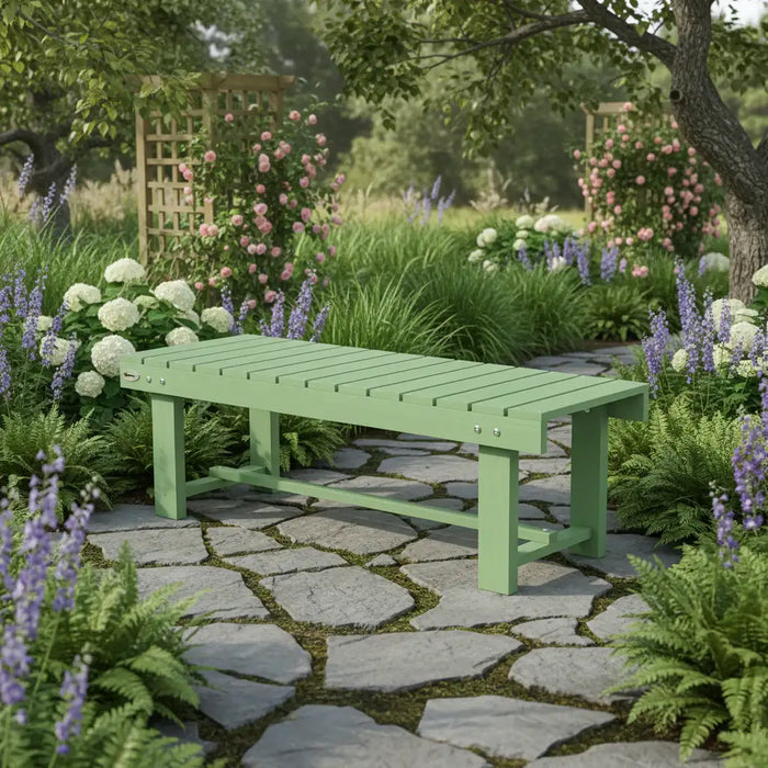 Light green wooden garden bench on stone pathway surrounded by lush green plants and colorful flowers