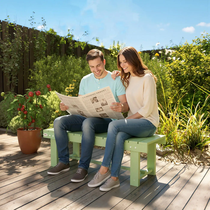 Couple sitting on light green wooden garden bench reading newspaper on sunny wooden deck with plants