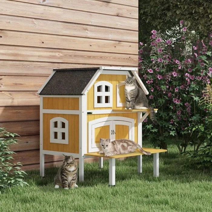 Yellow wooden outdoor cat house with terrace, jump platform, and three cats in garden