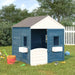 Blue and grey wooden outdoor playhouse with white trim in a grassy backyard, toys nearby