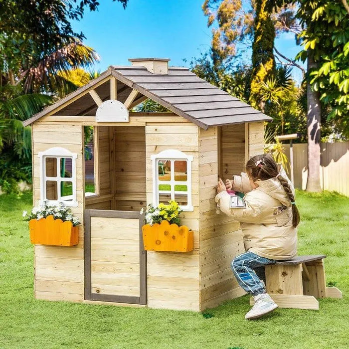 Wooden outdoor playhouse with flower boxes, bench, and child playing in garden