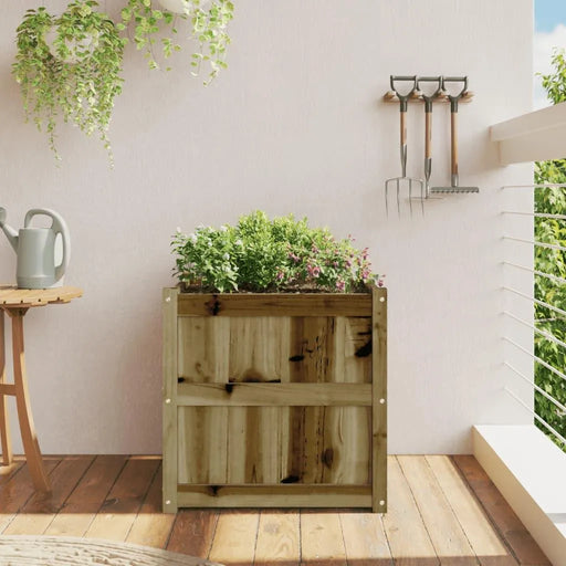 Wooden planter box with green plants on a balcony, pine deck, and garden tools on wall