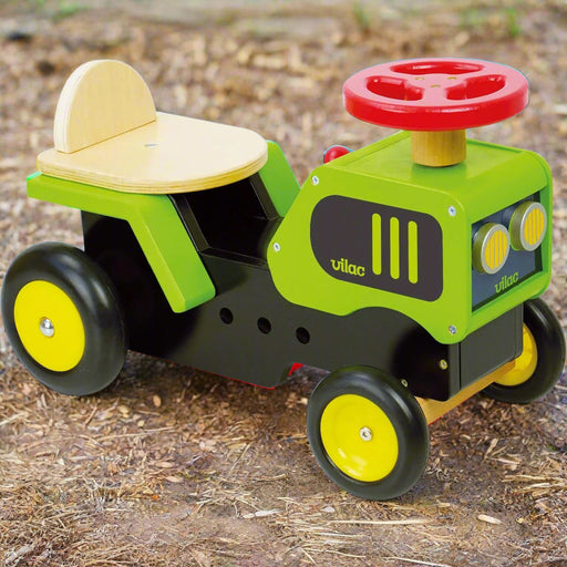 Wooden ride-on tractor toy with red steering wheel and yellow wheels on dirt ground