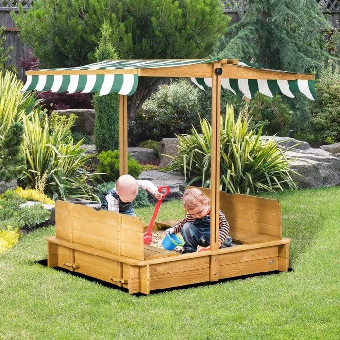 Kids playing in wooden sandbox with benches and green striped canopy in garden