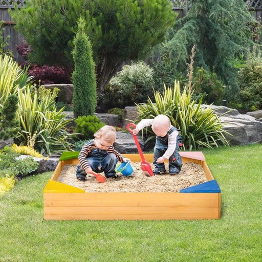 Wooden sandbox with four colorful corner seats, two toddlers playing, garden background