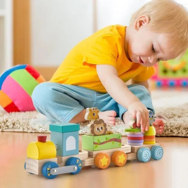 Toddler playing with wooden stackable train set and animal blocks on the floor