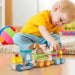 Toddler playing with wooden stackable train set and animal blocks on the floor