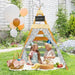 Kids in party hats sitting inside a wooden Montessori teepee tent outdoors with picnic food