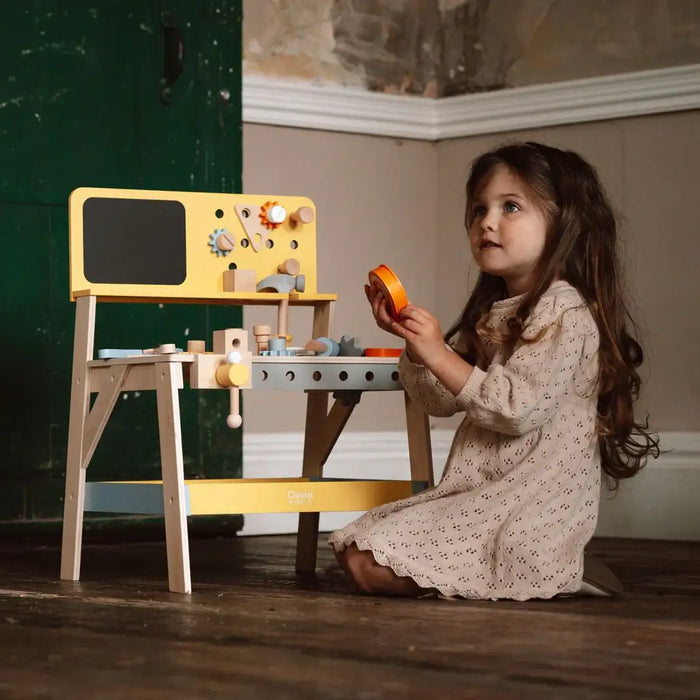 Young girl playing with wooden tool bench carpentry playset indoors