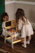Two children playing with a wooden tool bench carpentry playset on a wooden floor