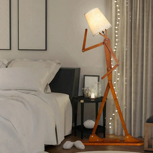 wooden tall floor lamp shaped like a walking person with lampshade head in a cozy bedroom