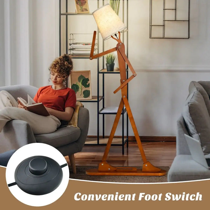Tall wooden floor lamp shaped like a walking person with fabric shade next to a woman reading on gray sofa