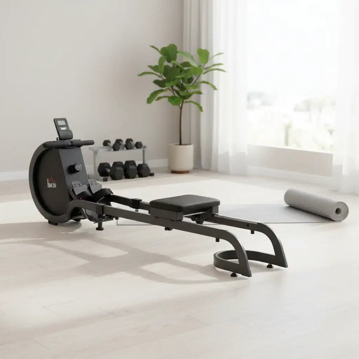 Black rowing machine with a visible brand logo in a plush lounge with weights and plant in the background