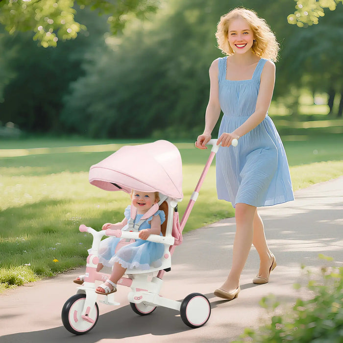 Woman pushing a child in a pink stroller along a path in a park.