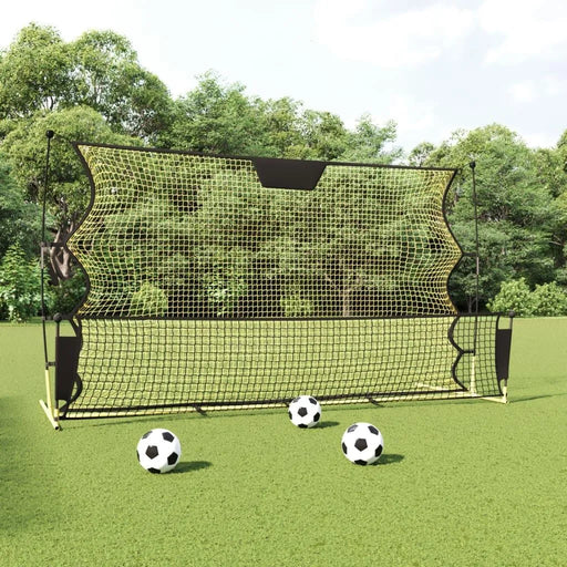 Yellow and black football rebounder net with soccer balls on green field outdoors
