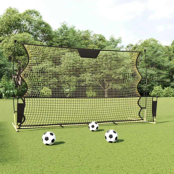 Yellow and black football rebounder net with soccer balls on green field outdoors