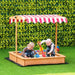 Kids playing in a yellow wooden sandbox with red canopy on green artificial grass
