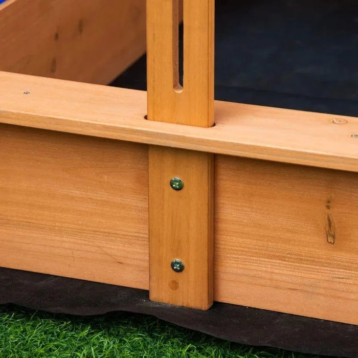 Close-up of yellow wooden sandbox with adjustable canopy frame on artificial grass