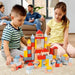Kids building a colorful wooden block castle set on a carpeted floor indoors