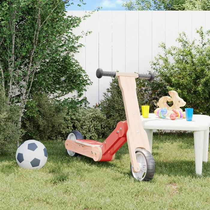 Red and black 2-in-1 kids scooter balance bike on grass beside soccer ball and play table outdoors