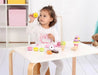 Child playing with wooden ice cream and dessert playset on a white table indoors