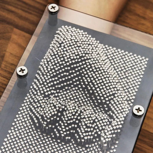 3D metal pin art impression frame desk toy with shiny silver pins on wooden surface